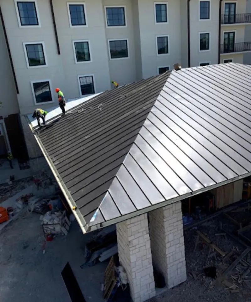 Crew installing standing seam metal roof panels on a commercial project in Noble